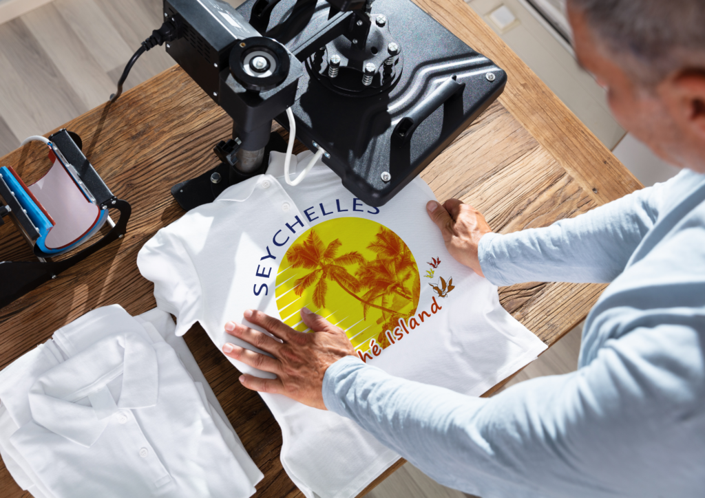 Aufpressservice-1adesign-siegen Ein weißes T-Shirt, welches mit Hilfe einer Transferpresse bedruckt wird